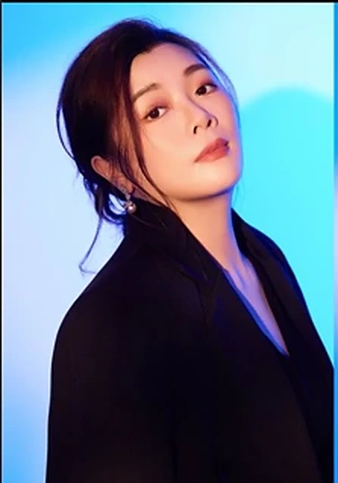 Eileen in a black blazer against a blue backdrop